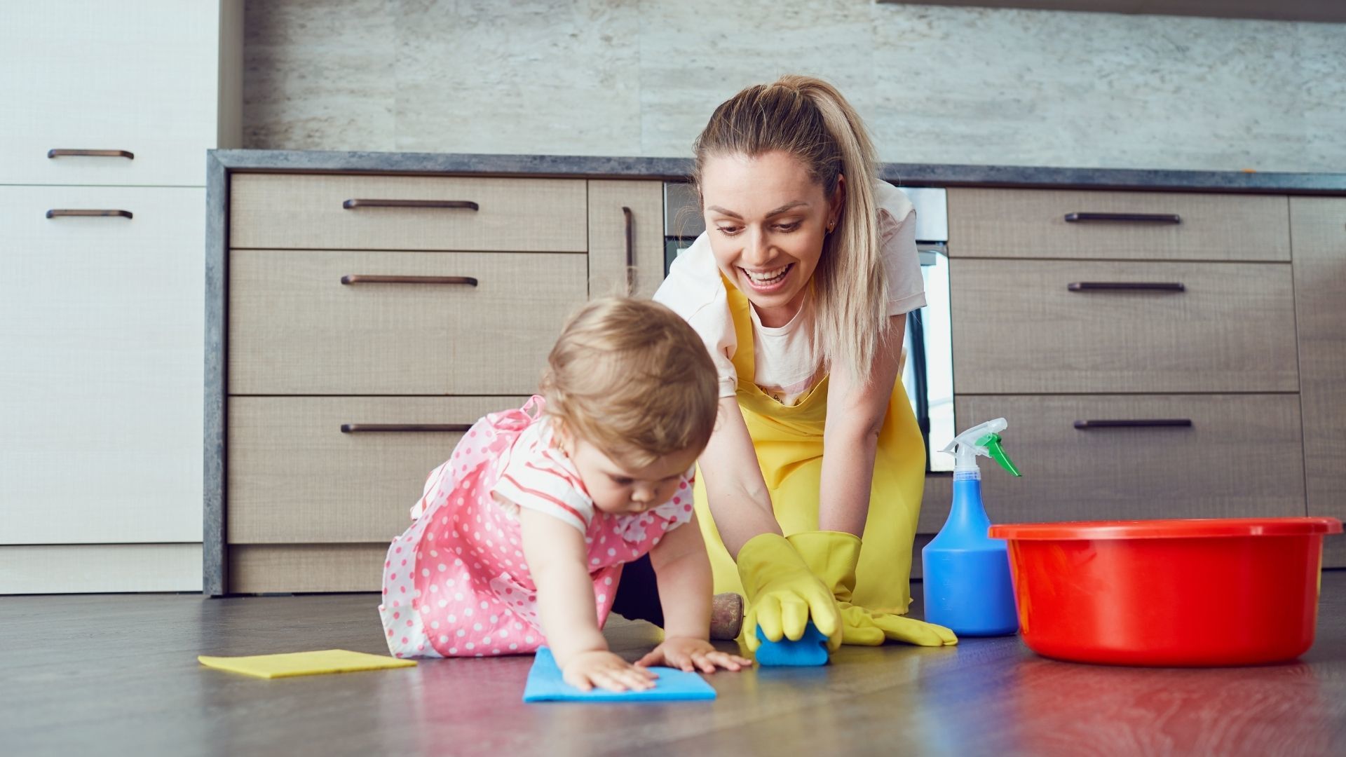 mamma con la figlia che puliscono il pavimento sorridenti